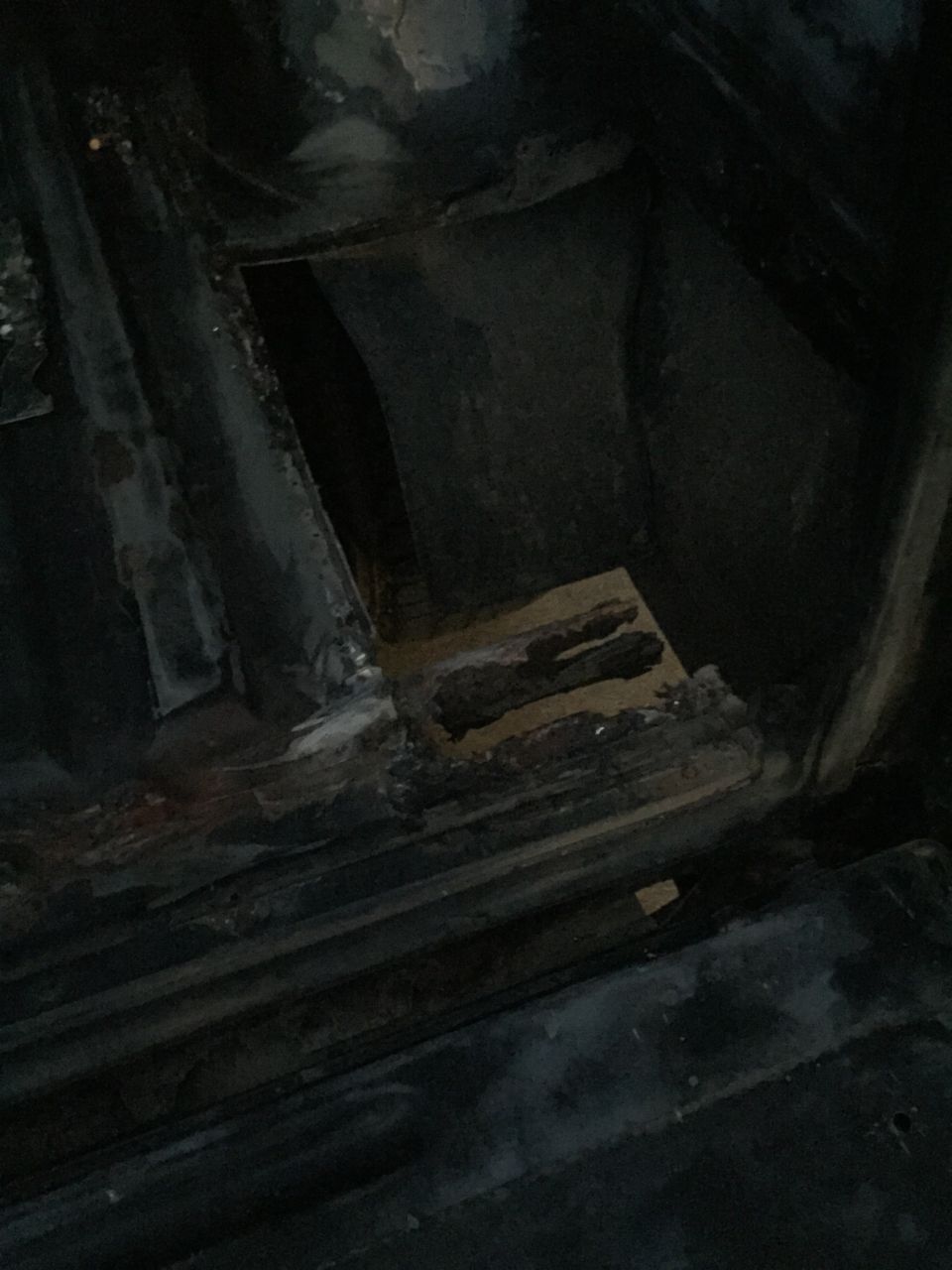 Interior view of a vehicle floor with metal components and debris.