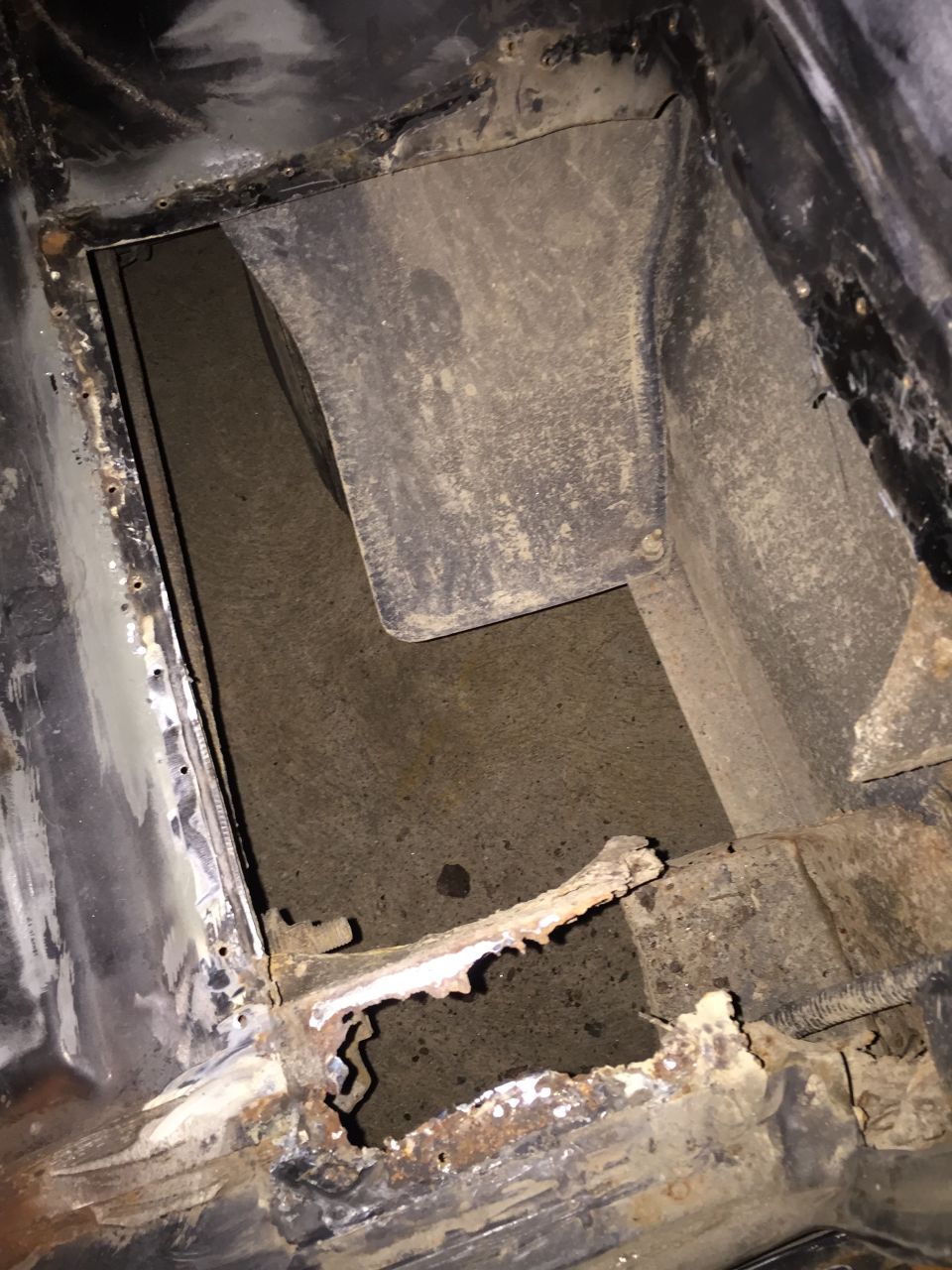 Severely rusted and corroded vehicle frame with a large hole.