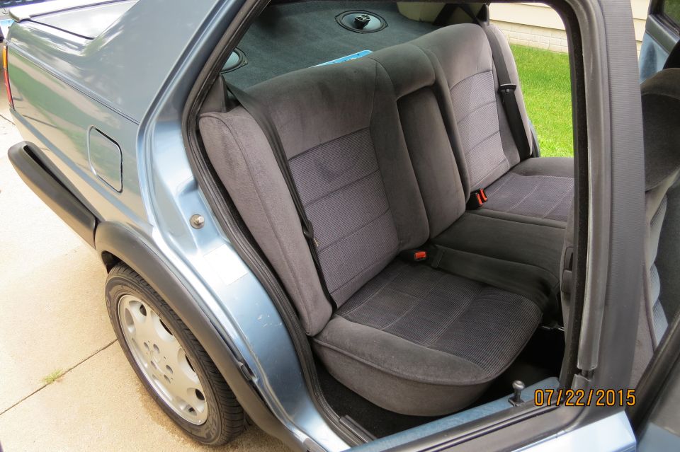Interior rear seats of a light blue Volkswagen Jetta, grey fabric with pinstripe pattern.