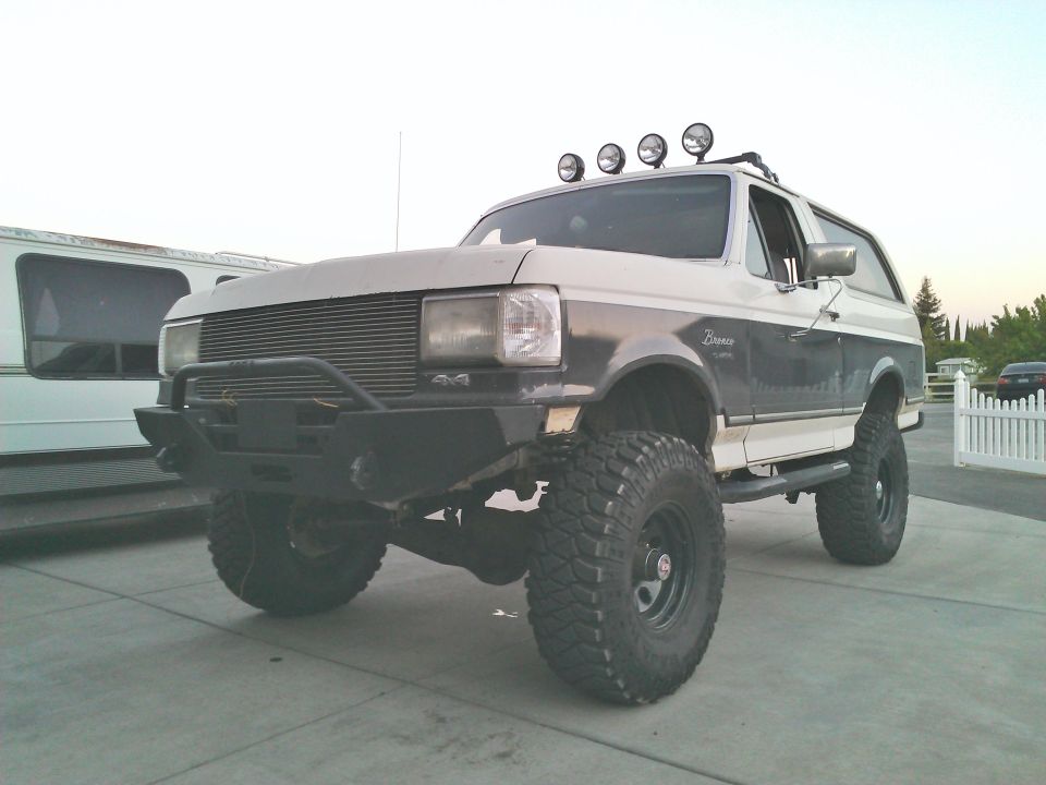 Lifted 1989 Ford Bronco with aftermarket bumper and roof lights.