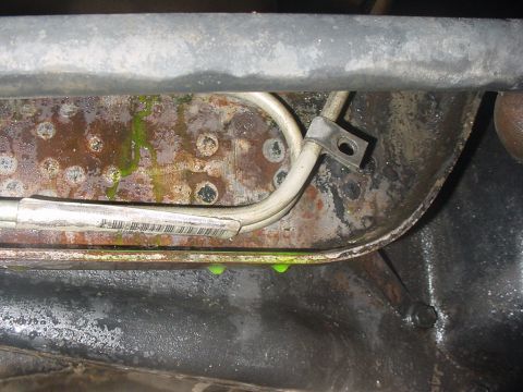 1988 Ford Bronco - Green coolant is seen leaking from a metal component, which has a visible barcode. The registry claims it is a 1988 Ford Bronco.