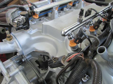 1995 Ford Bronco - A close-up view of the fuel injection system on a silver engine. The chrome fuel rails are visible with orange fuel injectors attached.