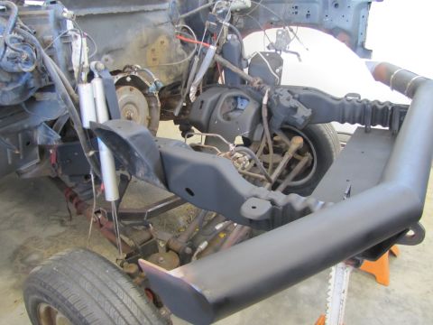 1995 Ford Bronco - The front suspension and frame of a vehicle undergoing restoration, likely a 1995 Ford Bronco, is shown with black painted components and v…