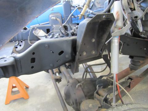 1995 Ford Bronco - The underside of a vehicle, likely a 1995 Ford Bronco, is shown with the frame, suspension components, and rear axle visible. An orange jac…