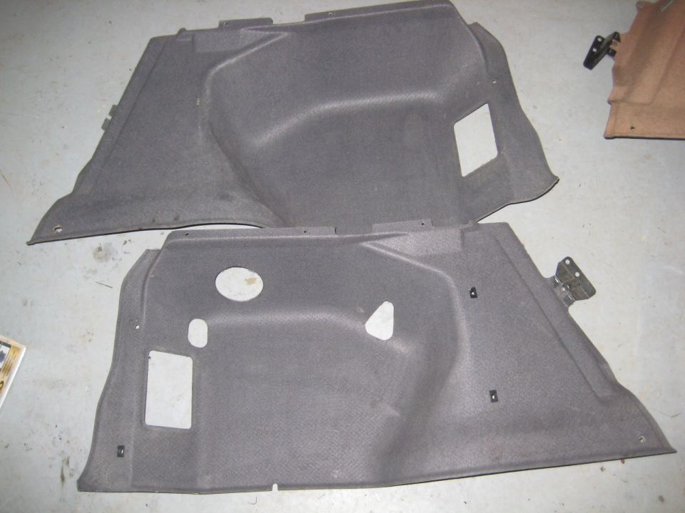 Two dark grey plastic interior trim panels for a vehicle cargo area
