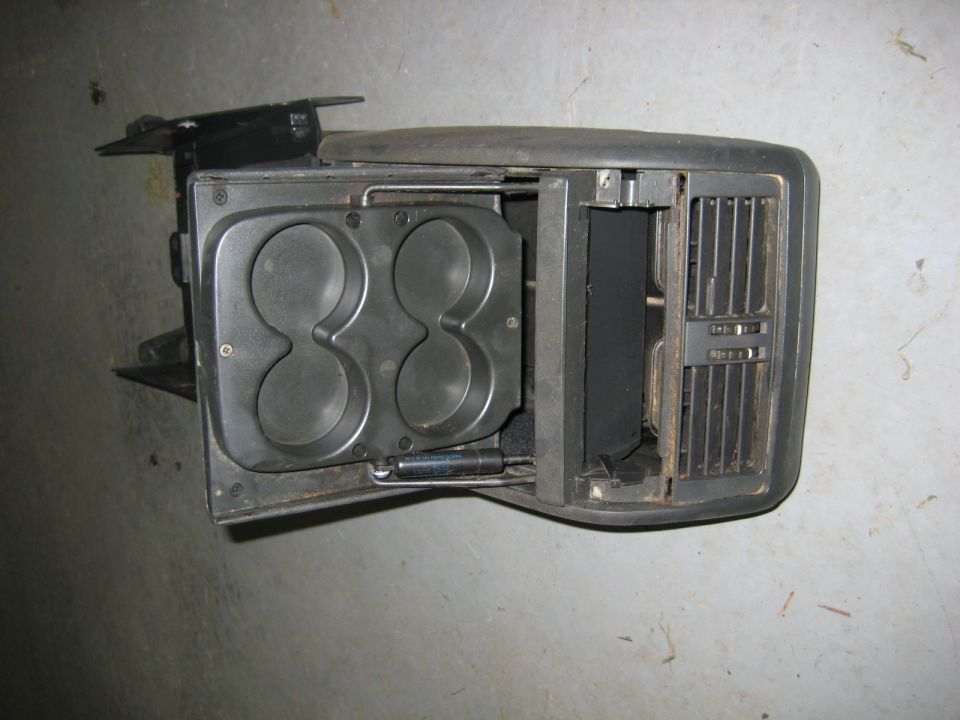 Black automotive center console part with dual cup holders and air vent