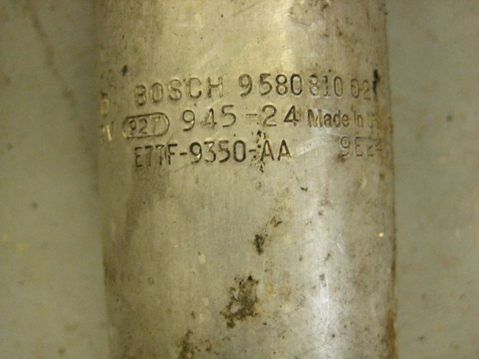 Embossed text on a dirty metal cylinder: BOSCH 9580810 021 (927) 945-24 Made in E77F-9350-AA 9E24