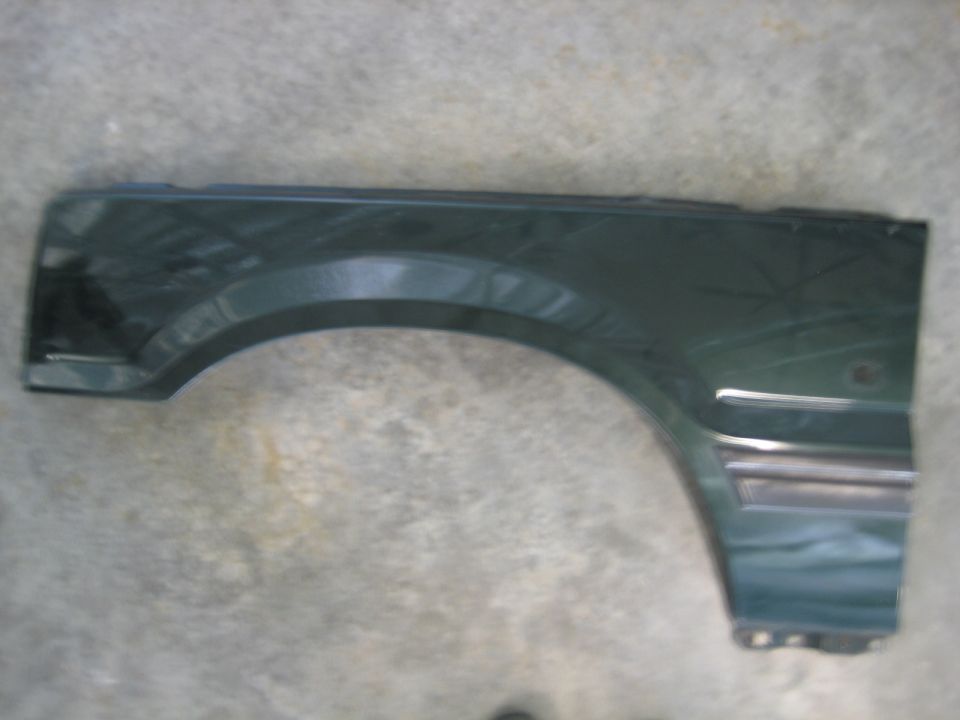 Dark green vehicle fender with chrome trim, side view.