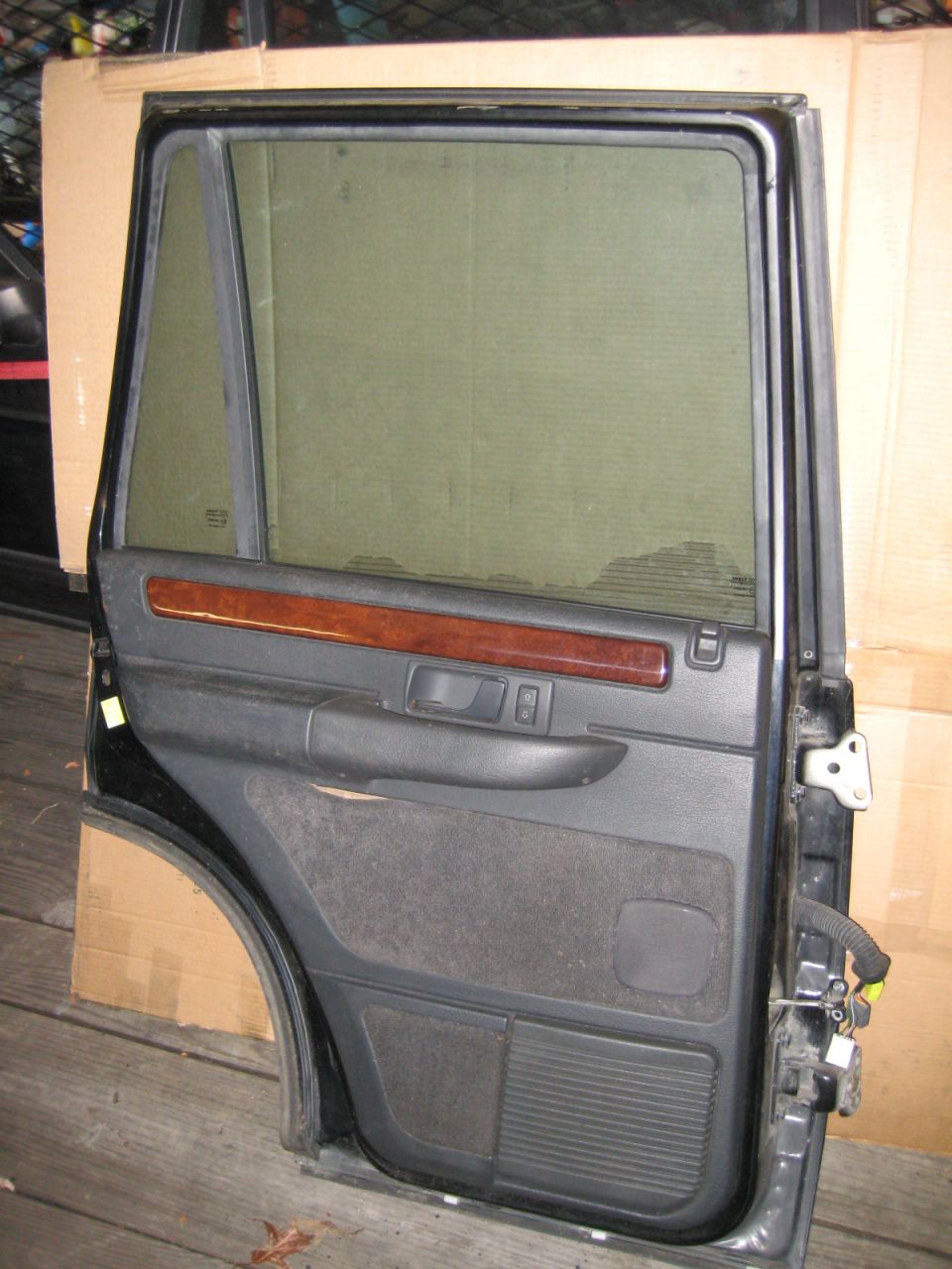 Interior of a disassembled rear SUV door with wood trim and fabric panels.