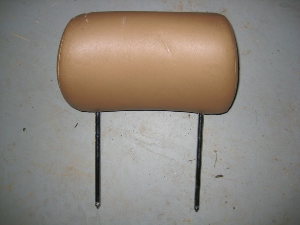 Tan leather vehicle headrest with chrome posts on concrete.