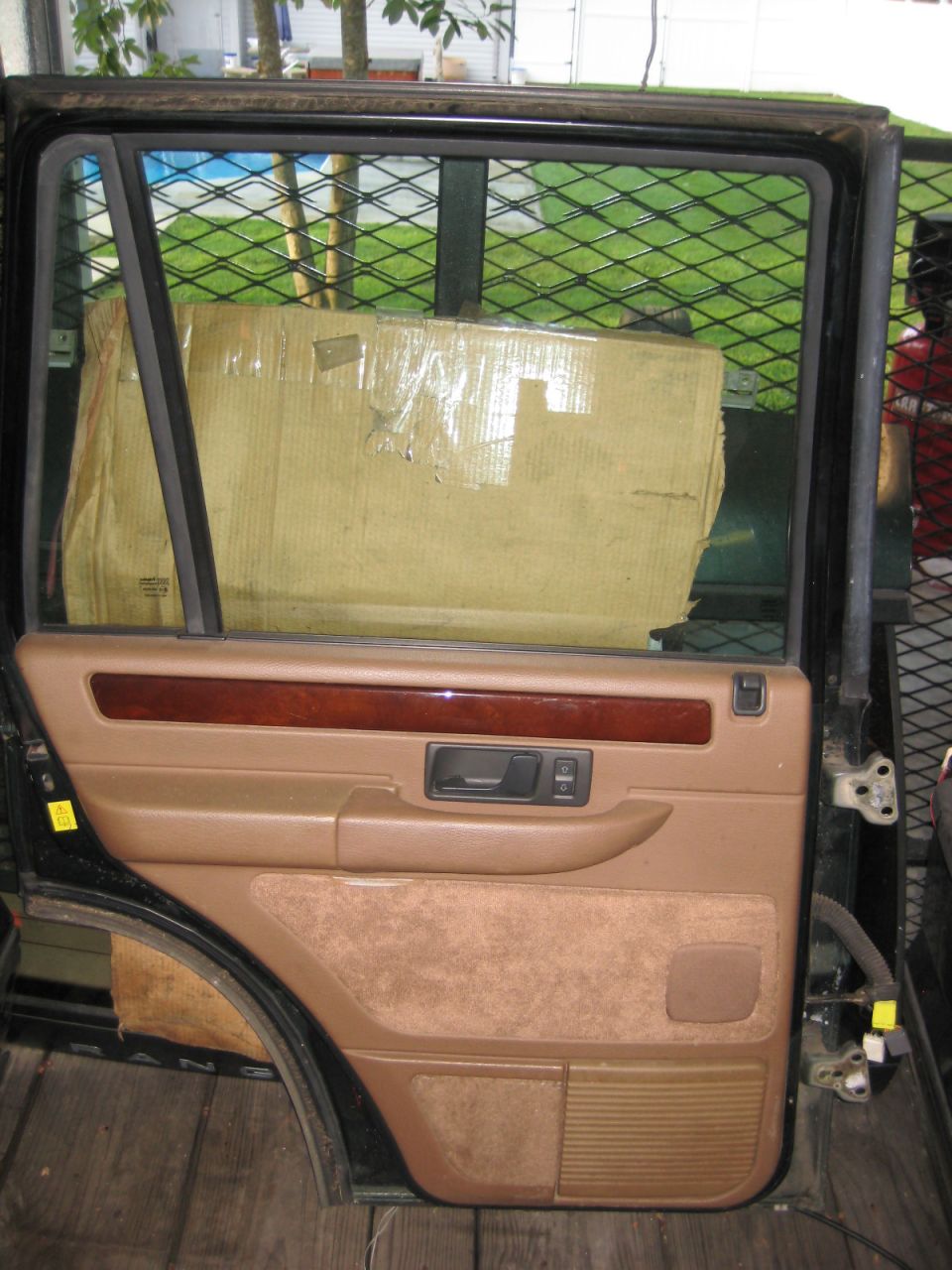Interior driver's side door panel of a Range Rover with tan upholstery and wood trim.