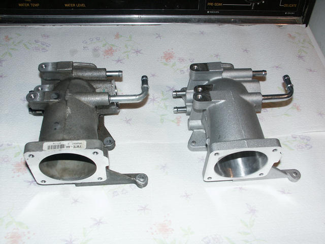 Two aluminum throttle bodies side by side comparing small and larger inlet bores