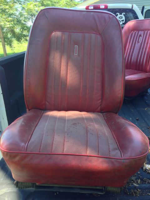 1979 Ford Bronco - A pair of red vinyl bucket seats are shown in the bed of a pickup truck. The seats have vertical stitching and appear to be from an older v…