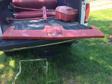 1979 Ford Bronco - A red aftermarket visor is laid across the tailgate of a white pickup truck. The visor has amber marker lights and appears to be made of pl…