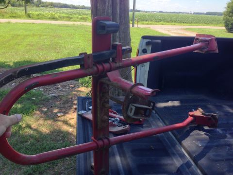 1979 Ford Bronco - A red metal contraption, possibly a trailer hitch or farm implement, is resting in the bed of a black pickup truck. The truck is parked out…