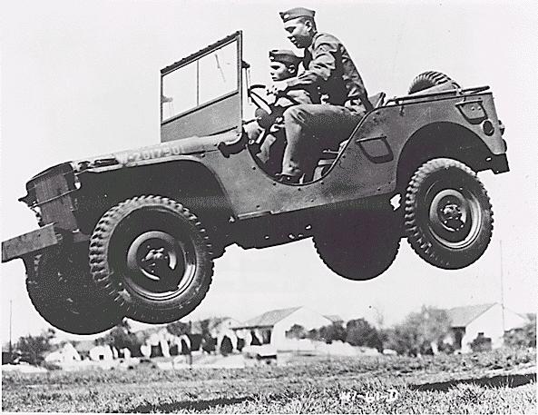 Military Jeep jumping in the air with two people inside.