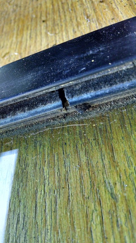 1992 Ford Bronco - A close-up view shows a damaged black rubber seal and the weathered wooden interior of a vehicle, possibly a 1992 Ford Bronco.