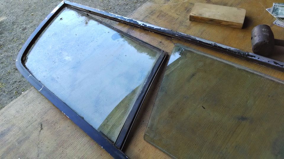 Two pieces of vehicle glass, one in a frame, on a wooden surface.