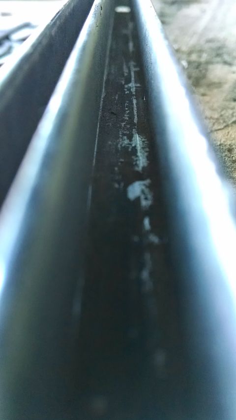 1992 Ford Bronco - Close-up view of the inside of a metal channel, possibly a roof rack or frame rail, showing wear and some white residue. The channel is dar…