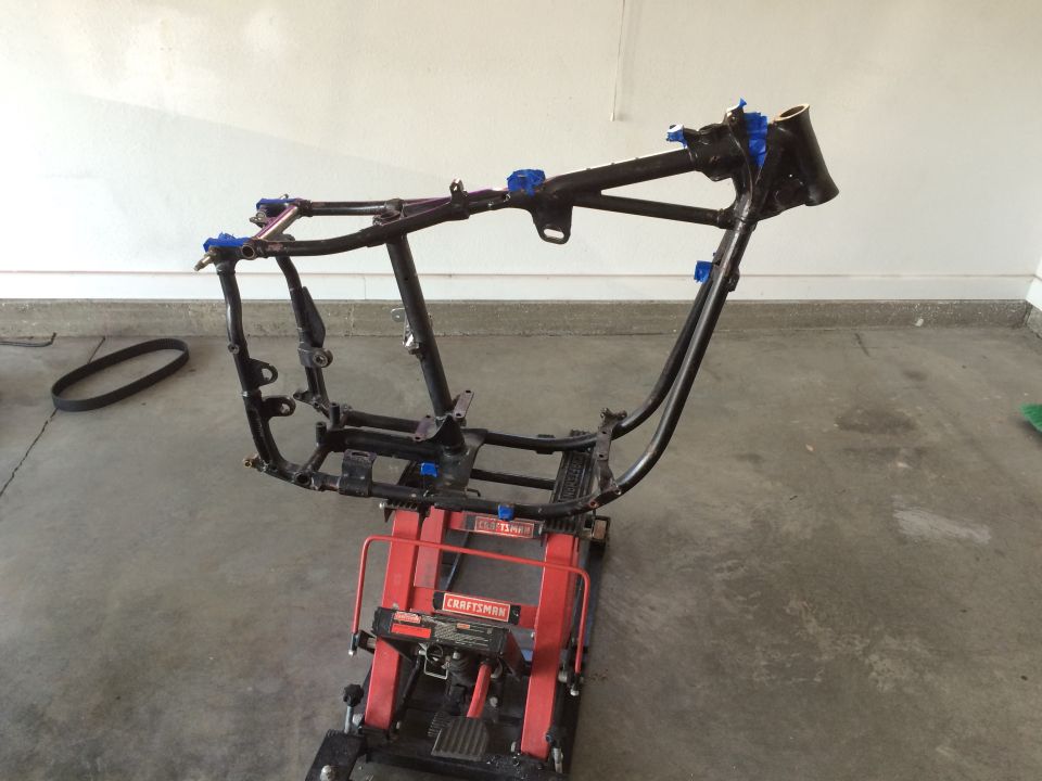 Black motorcycle frame on a red lift with blue tape