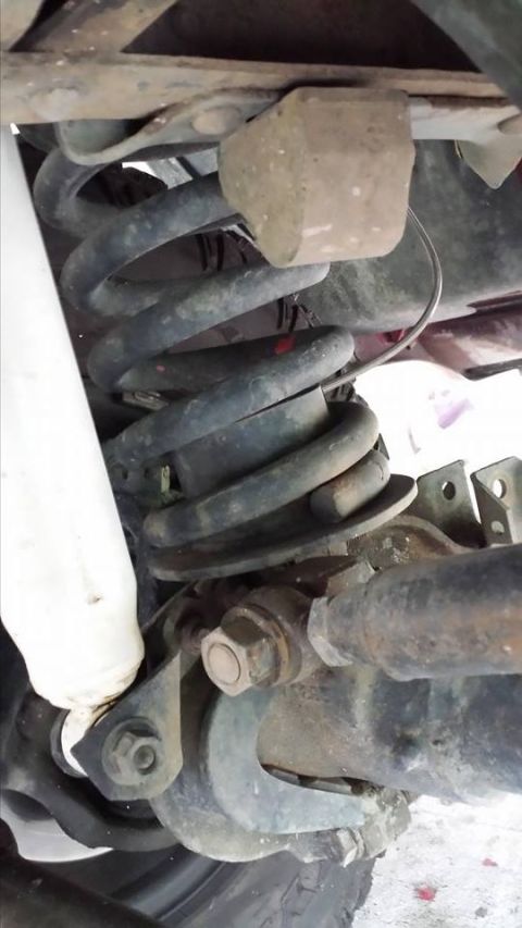 1995 Ford Bronco - This is a close-up, low-angle view of the rear suspension components of a 1995 Ford Bronco. Visible parts include the coil spring, shock ab…