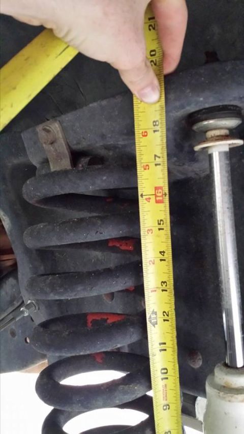 1995 Ford Bronco - A yellow measuring tape is held against a black coil spring, with the measurement showing approximately 19.5 inches. The spring appears to…