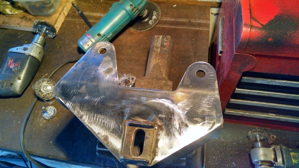 Metal bracket being cleaned with power tools.