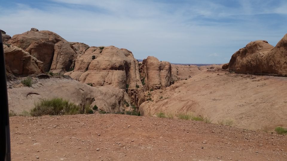 Desert landscape with sandstone rock formations and a dry, rocky ground.