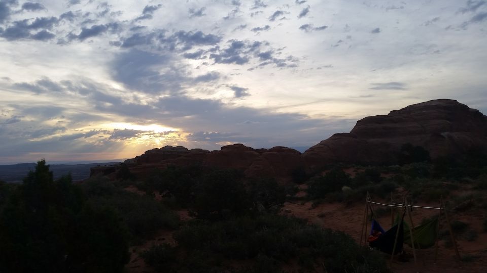 Sunset over rocky desert landscape with a hammock set up.