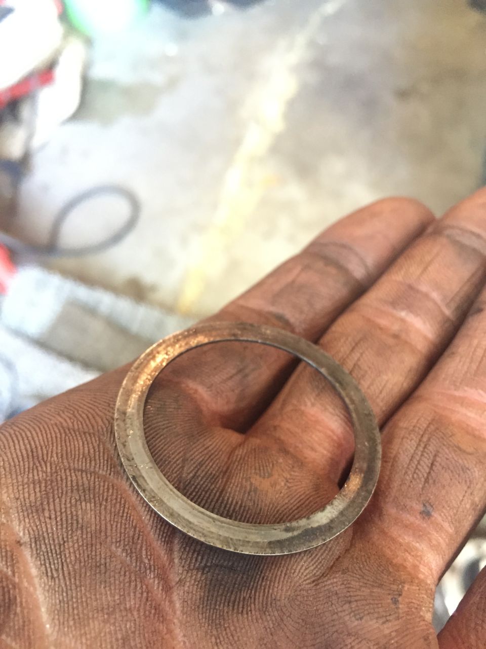 Dirty hand holding a metal washer