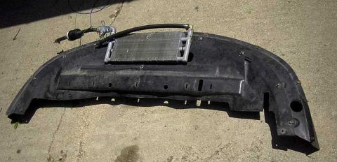 1997 Ford Taurus - Car bumper with transmission cooler and hoses, resting on concrete.