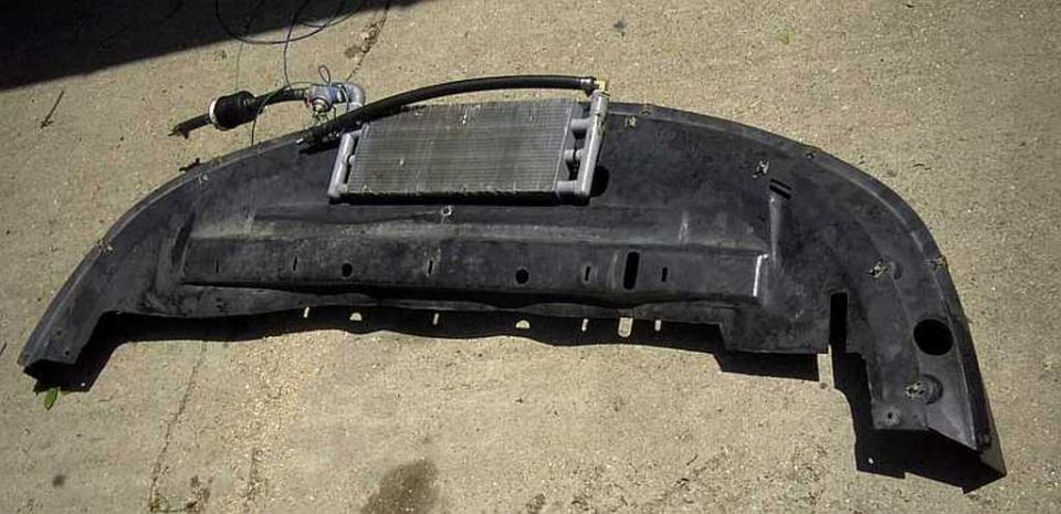 Black car bumper with a transmission cooler mounted on top, hoses attached