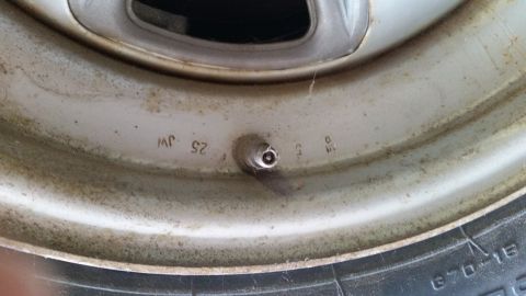 2015 Chevrolet new - A close-up view of a dirty silver wheel rim with markings and a tire. The rim has embossed text including "JW 25" and "9 5".
