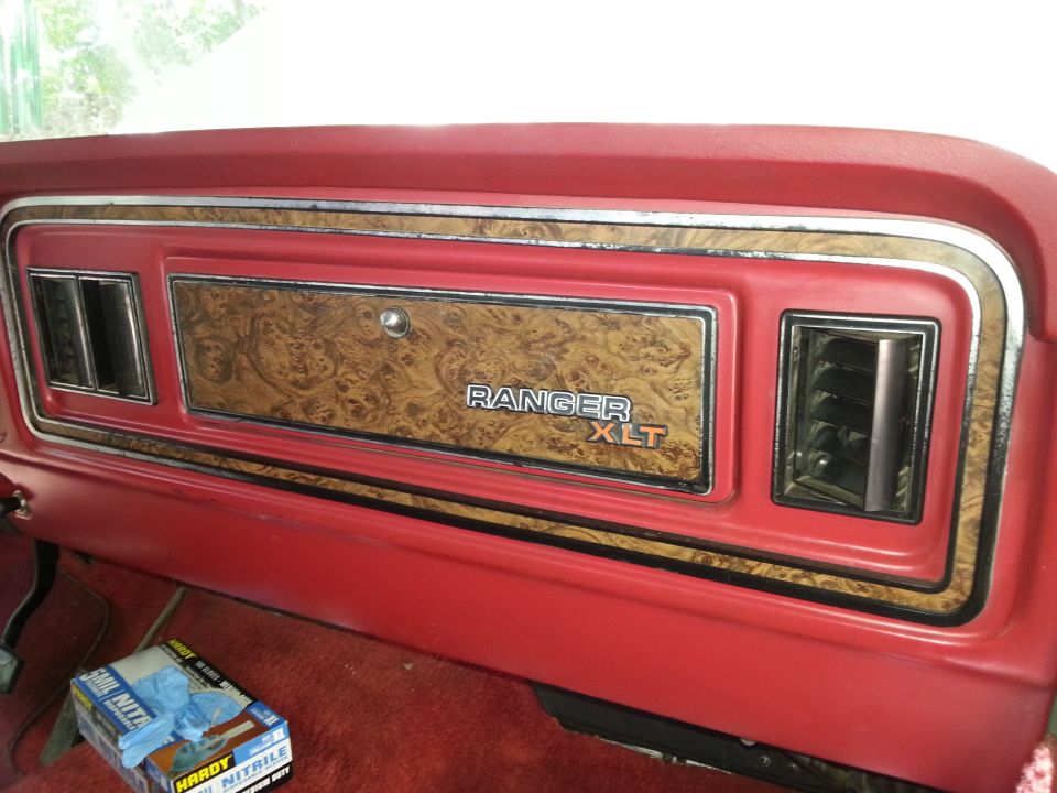 Close-up of a vintage Ford Ranger XLT dashboard with wood grain trim and red accents.