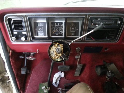 1978 Ford Bronco - The interior of a vintage Ford Bronco shows the dashboard with gauges, air vents, radio, and steering column. The floor is covered in red c…