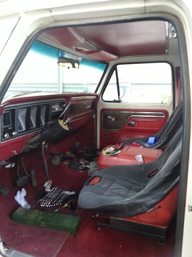 1978 Ford Bronco - The interior of a classic Ford truck or SUV, likely from the late 1970s, is shown with red carpeting and door panels. A racing seat has bee…