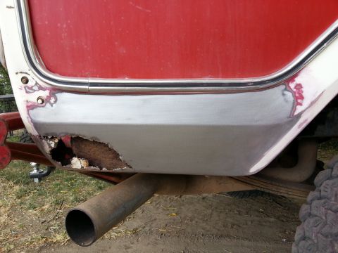 1978 Ford Bronco - A close-up view of the rear corner of a red and white vehicle shows significant rust damage and body repair work. An exhaust pipe extends f…