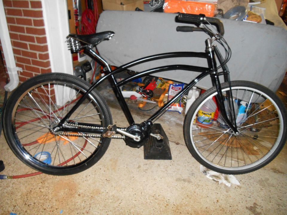 Black cruiser bicycle with sprung seat and spoked wheels, side view.