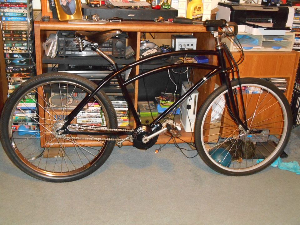 Black cruiser bicycle with motor, parked indoors.