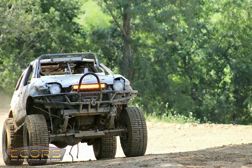 Front view of a modified off-road buggy with a light bar and large tires on a dirt track