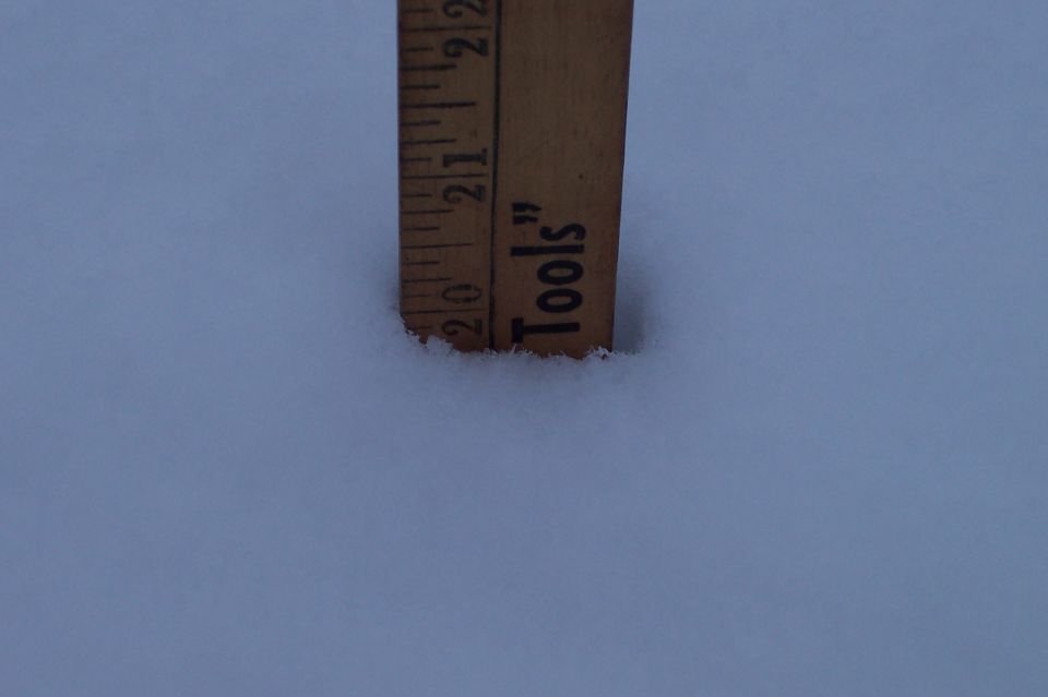 Wooden ruler stuck in snow showing about 20 inches of depth