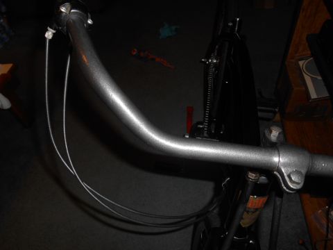 Gray bicycle handlebars with silver brake cables, viewed from the front
