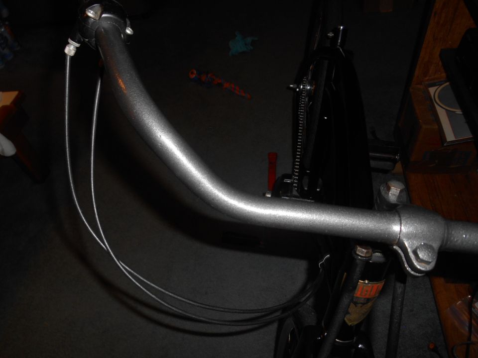 Gray bicycle handlebars with silver brake cables, viewed from the front