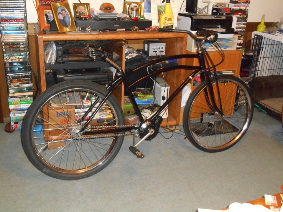 Black cruiser bicycle with chrome spokes and handlebars, parked indoors