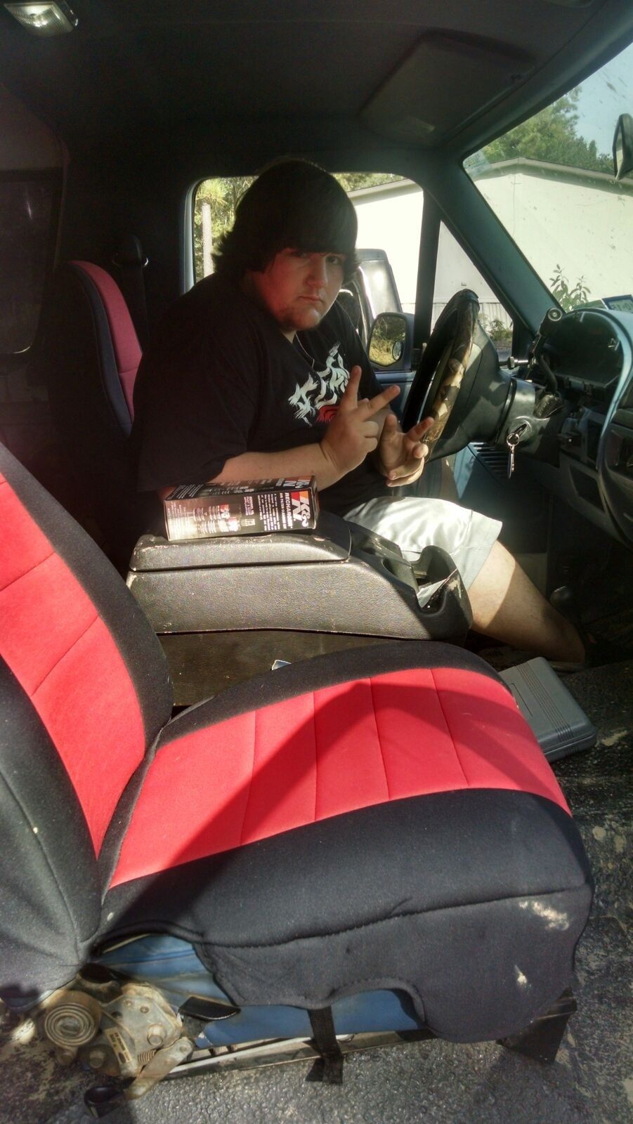 Person wearing a beanie sits in the driver's seat of a 1996 Ford Bronco, holding up two fingers