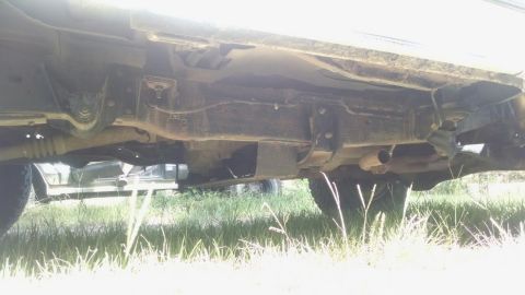 1996 Ford Bronco - The undercarriage of a vehicle is shown, with another vehicle partially visible in the background.