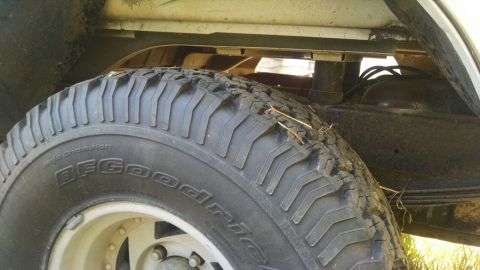 1996 Ford Bronco - Close-up view of a BFGoodrich Baja Champion tire, showing tread detail and part of the vehicle's undercarriage.