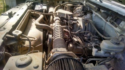 1996 Ford Bronco - A close-up view of a vehicle's engine bay, showing various mechanical parts and fluid reservoirs.