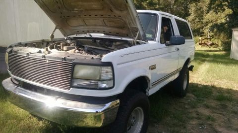 1996 Ford Bronco - White 1996 Ford Bronco with hood open, showing the engine bay, parked outdoors.
