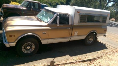 1968 Chevrolet C/K Pickup - Side view of a 1969 Chevrolet C/K Pickup truck with a camper shell, parked next to another truck.